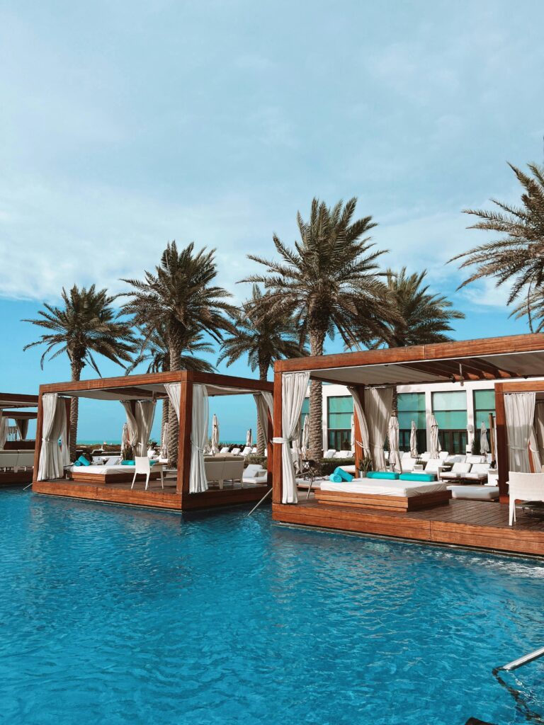 Elegant cabanas by the pool with palm trees at Saadiyat Beach Club, Abu Dhabi.