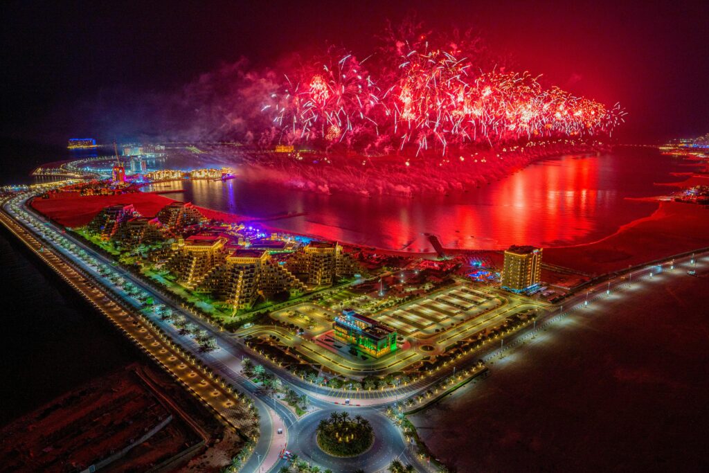 pexels-photo-10483824-10483824 Vibrant aerial view of fireworks lighting up Ras al Khaimah's waterfront at night, showcasing the cityscape and illuminated reflections.