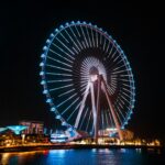 Illuminated Ferris wheel in Dubai at night showcasing vibrant cityscape and architectural beauty.