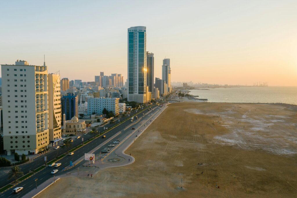 pexels-photo-8319452-8319452-1 Aerial view of a coastal city with skyscrapers, streets, and sea at sunset, showcasing urban life.