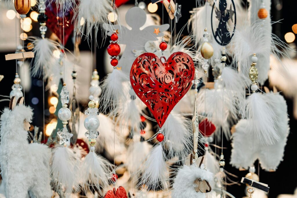 A vibrant display of holiday decorations featuring a red heart ornament surrounded by white feathers and lights.