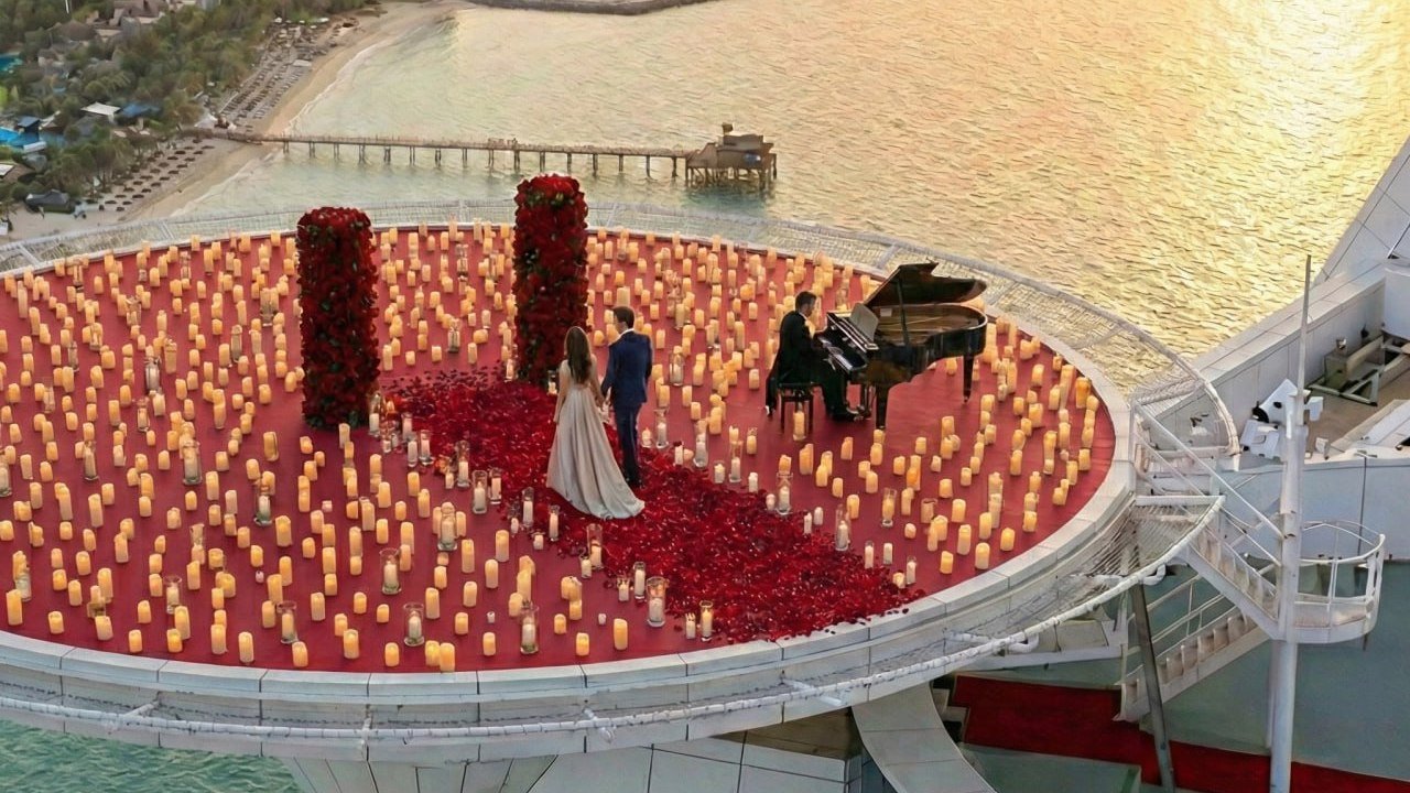 Couple and pianist on the Burj Al Arab helipad covered in candles and red rose petals at sunset