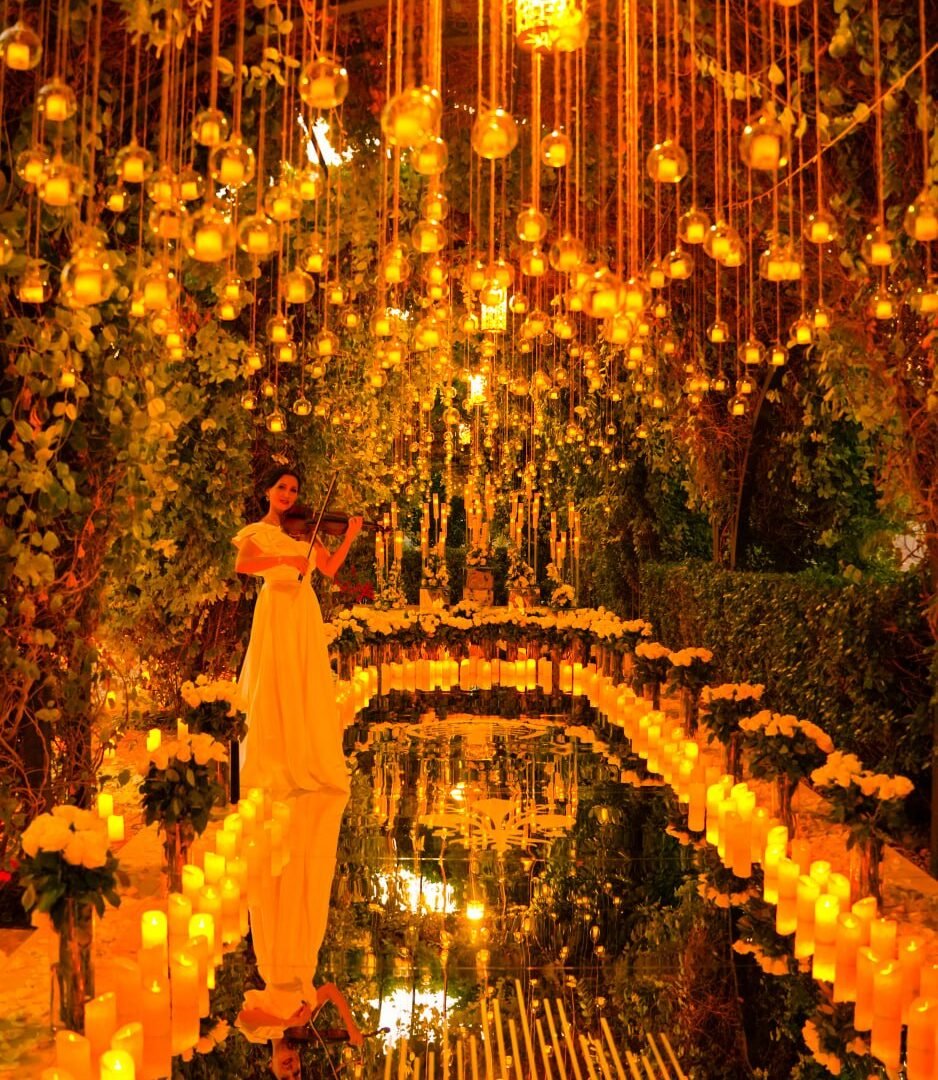 Candlelit mirrored aisle under hanging lanterns with violinist